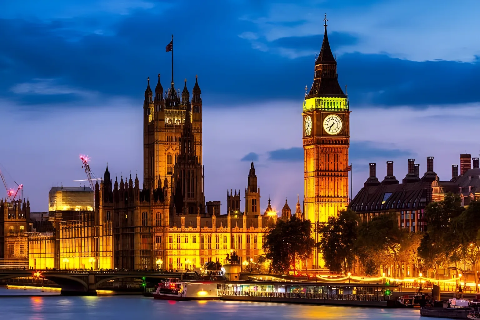 The Palace of Westminster and Elizabeth Tower illuminated beside the River Thames at dusk